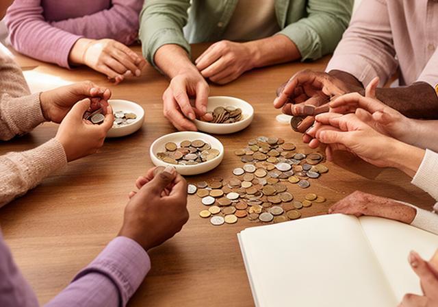 Handen van verschillende gezinsleden die samen munten sorteren aan een tafel in Terneuzen